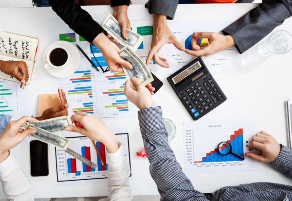 Picture of businessmen's hands on white table with documents, coffee and drafts